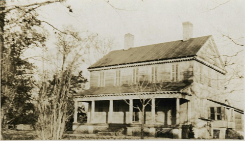 Old photograph of a two-story home with a wide front porch