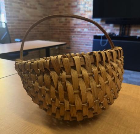woven hand basket made of wood with a handle, sitting on a table
